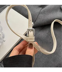 Détail de la boucle argentée réglable et des coutures sur la bandoulière en cuir beige