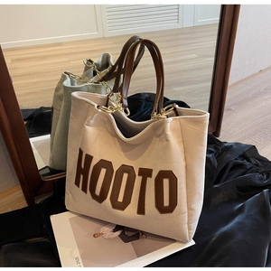 Detailed view of off-white corduroy tote bag with brown HOOTO patch and leather handles
