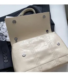 Detail of creamy white textured PU leather bag with silver magnetic snap closure