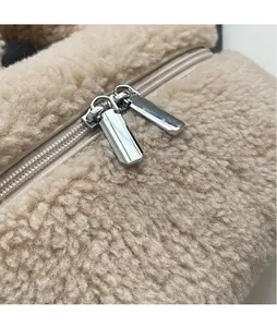 Détail des fermetures éclair en métal argenté lisse sur un sac seau en peluche beige