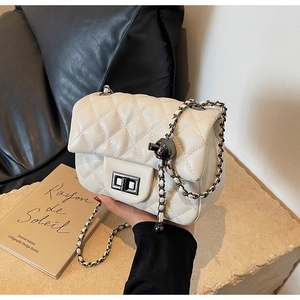 Close-up of white quilted leather bag with metallic ball chain lock and turn-clasp detail