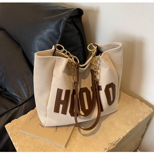 Detail of hooto patch embroidery on cream corduroy tote bag with chain strap