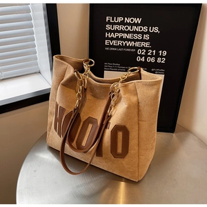Detail of corduroy tote bag with leather letter patch and metal chain strap