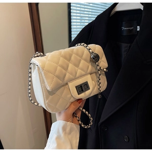 Detail of white quilted crossbody bag with metal sphere buckle and chain strap
