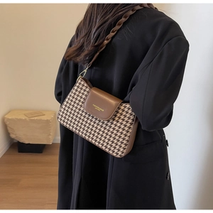 Detail view of houndstooth fabric underarm bag with woven leather strap and golden logo