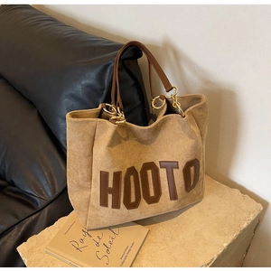 Detail of brown corduroy tote bag featuring leather HOOTO patch and gold metal hardware