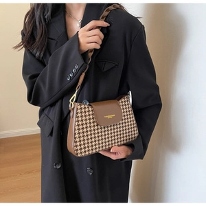 Detail of vintage houndstooth shoulder bag with leather flap and woven strap
