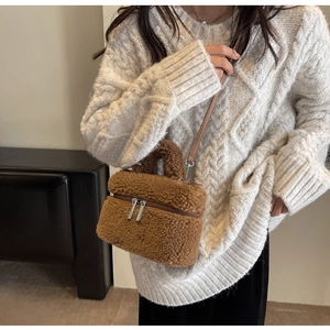 Détail d'un sac seau en peluche marron avec bandoulière en cuir porté par un mannequin