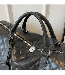 Detail of black quilted travel bag featuring reinforced handles and smooth metal zippers