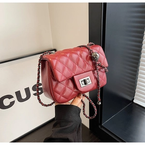 Close-up of red quilted leather chain bag with metallic ball and turn-lock closure