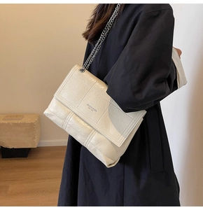 Detail of cream chain shoulder bag with quilted square stitching and silver metal strap