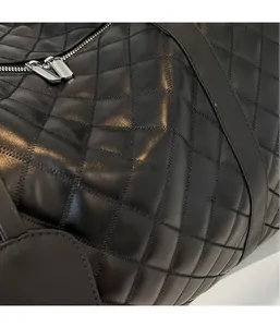 Detail view of black quilted PU travel bag featuring silver metal double zippers and fabric