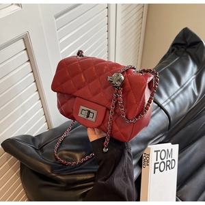 Detail of red quilted leather crossbody bag featuring grey metal chain and ball charm