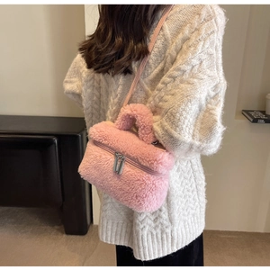 Détail d'un sac seau en polaire rose avec fermeture éclair argentée et bandoulière