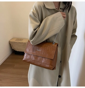 Detail view of brown chain shoulder bag with quilted stitching and metallic silver strap