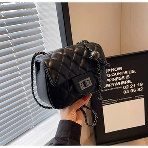 Close-up of black quilted leather bag with chain strap and metal ball adjuster detail