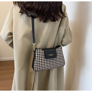 Detail of houndstooth crossbody bag with black leather flap and gold fashion logo