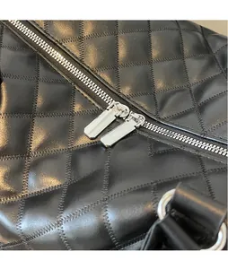 Detail of silver polished metal zipper hardware on black quilted travel bag surface
