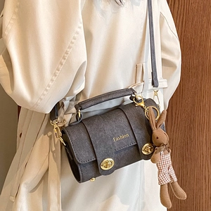 Retro grey matte crossbody bag with gold clasps and rabbit charm on beige trench coat