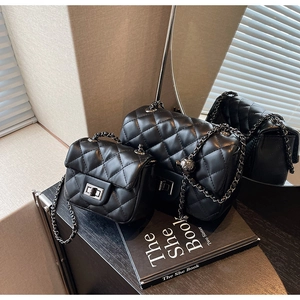 Detail of two black quilted chain bags with sleek metal turn-lock closures and polished finish