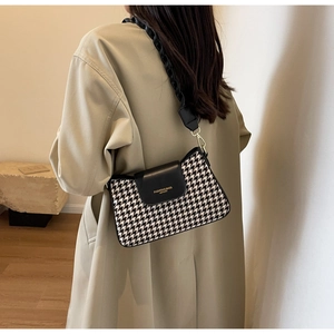 Detail of stylish houndstooth shoulder bag featuring a unique pleated wide strap
