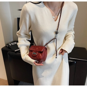 Detail of red quilted micro bag with silver turn-lock and leather chain strap