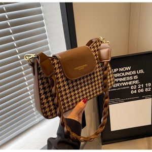 Close-up of houndstooth patchwork texture with braided strap and gold hardware