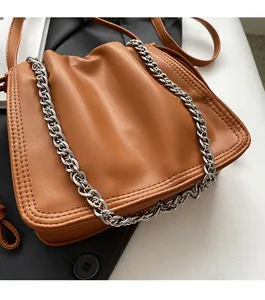 Dettaglio della borsa a secchiello in pelle caramello con design a pieghe e catena