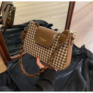 Detail of houndstooth patchwork shoulder bag with leather flap and woven handle