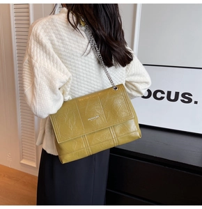 Detail of yellow quilted leather bag with silver chain strap and metal brand logo