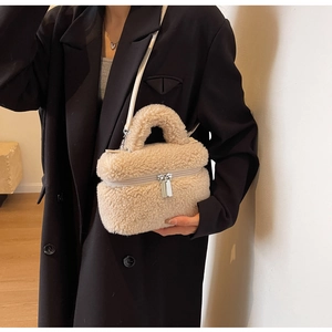 Détail du sac seau en peluche beige avec double fermeture éclair et texture molletonnée