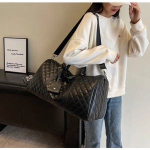 Detail of large black quilted faux leather travel bag with adjustable strap and handles