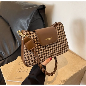 Detail of brown houndstooth underarm bag with leather trim and gold hardware accents