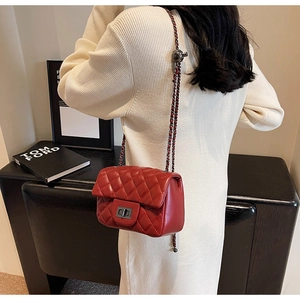 Detail of dark red quilted crossbody bag featuring silver twist lock and chain strap