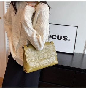 Detail of olive green pleated leather chain bag showing luxury texture and flap design
