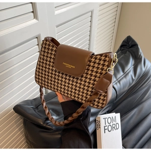 Detail of vintage houndstooth fabric and brown leather handle on a stylish crossbody bag