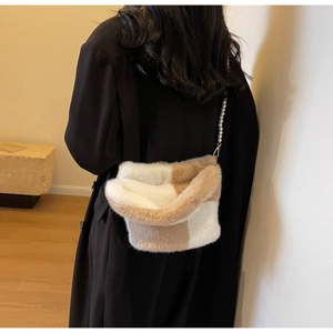 Detail of plush checkered bucket bag with pearl strap on a black winter coat