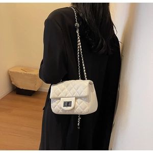 Detail of quilted diamond pattern on cream leather bag with silver chain strap