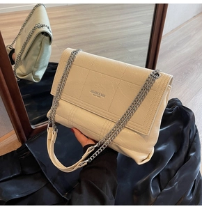Detail shot of the cream chain shoulder bag with quilted texture and silver hardware