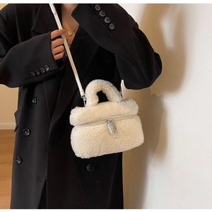 Gros plan d'un sac seau en peluche crème avec fermetures éclair et bandoulière