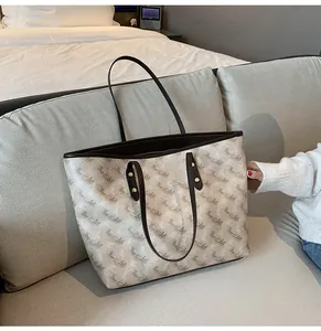 Close-up of beige tote bag with horse carriage pattern and brown leather straps