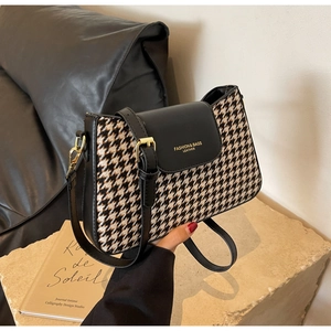 Detail of vintage houndstooth fabric texture and golden logo on crossbody bag