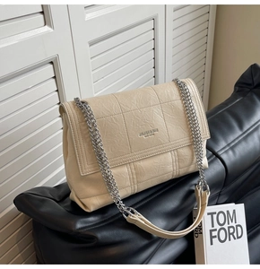 Detail of beige quilted faux leather texture and silver chain strap on a flap shoulder bag