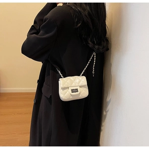 Detail of white quilted mini bag with silver twist lock on black blazer outfit