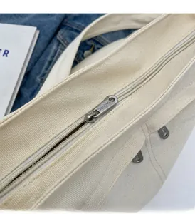 Detailed close-up of smooth metal zipper closure on durable cream canvas tote bag