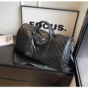 Macro detail of the quilted black travel bag showing diamond texture and metal hardware