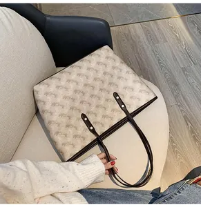 Top view of a beige canvas tote bag with brown straps placed on a wooden chair