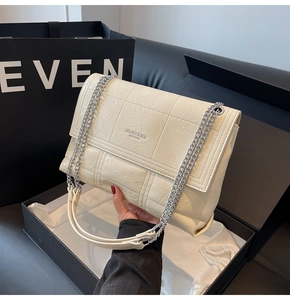 Detailed close-up of a quilted cream leather bag with silver chain and luxury gift packaging