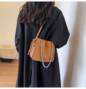 Vista posteriore di una modella con borsa a secchiello in pelle marrone e catena argento