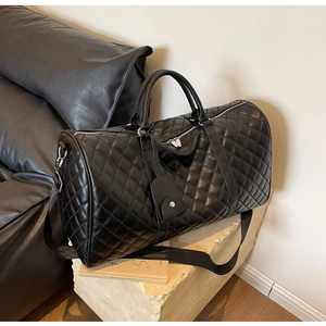Macro detail of black quilted leather duffel bag with silver hardware and logo tag